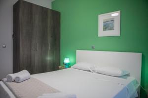 ein Schlafzimmer mit einem weißen Bett und einer grünen Wand in der Unterkunft Lak Peristeri Homes in Athen