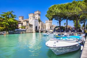a boat in the water in front of a castle at La Luce di Sirmione in Sirmione
