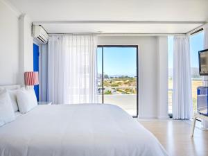 a bedroom with a white bed and a large window at La Splendida Hotel by NEWMARK in Cape Town