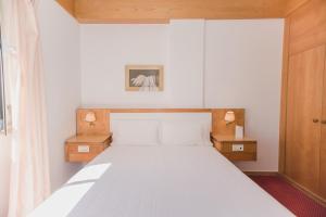 1 dormitorio con 1 cama blanca y 2 mesitas de noche en Albergaria Senhora do Monte, en Lisboa