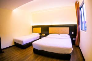 a hotel room with two beds and a window at Hotel Zuhra in Sibu