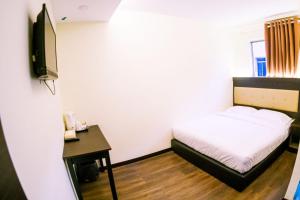 a bedroom with a bed and a desk and a tv at Hotel Zuhra in Sibu