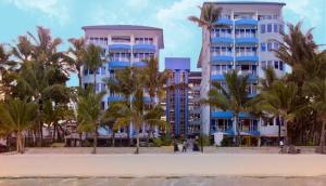 a building on the beach with palm trees in front of it at Bamburi Beach Studio Apartment B41 in Bamburi