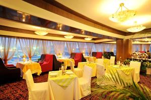 a restaurant with white tables and chairs and windows at Super House International in Beijing