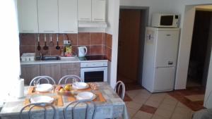 cocina con mesa, sillas y nevera blanca en Apartman Lovro, en Novalja