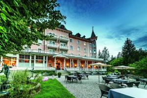 un hôtel avec des tables et des chaises dans une cour dans l'établissement Romantik Hotel Schweizerhof & Spa, à Flims