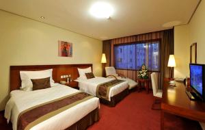 a hotel room with two beds and a desk and a television at Super House International in Beijing