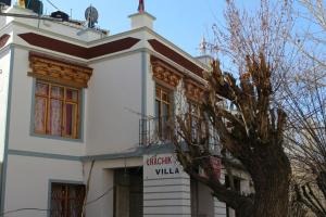 un edificio blanco con un árbol delante en Lhachik Guest House, en Leh