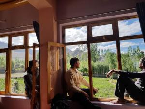 a man and a woman sitting on a bench in front of a window at Lhachik Guest House in Leh