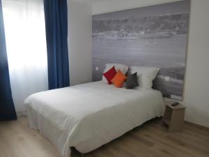 una camera da letto con un grande letto bianco con cuscini di Hotel Côte d'Opale a Étaples