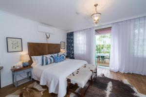 Un dormitorio con una gran cama blanca y una mesa en Drostdy Hotel en Graaff-Reinet