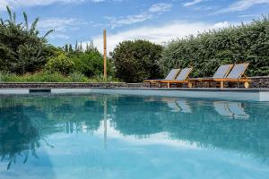 a swimming pool with two lounge chairs and the water at Quinta dos Peixes Falantes in Ribeira Grande
