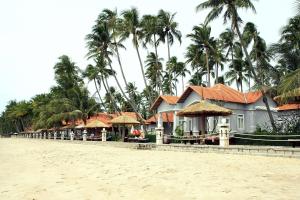 una fila de casas en la playa con palmeras en Muine Century Beach Resort & Spa, en Mui Ne