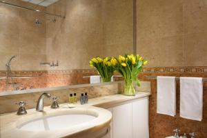 a bathroom with a sink and a vase of yellow flowers at UNA Hotels Hotel & Residence Contessa Jolanda Milano in Milan +18 photos