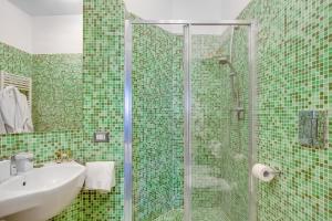 a green tiled bathroom with a sink and a shower at ALMA de Toledo Design Home Plebiscito in Naples
