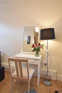 a desk with a vase of flowers and a mirror at King's Cross Comfy Studio in London