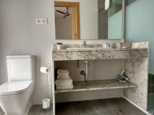a bathroom with a toilet, sink, and mirror at Hostal Enriqueta in Marbella