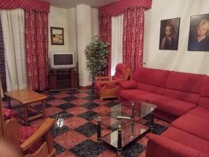 sala de estar con sofá rojo y TV en Hostal Rural Rambla, en Alcalá del Júcar