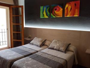 2 camas en una habitación con pinturas en la pared en Hostal Rural Rambla, en Alcalá del Júcar