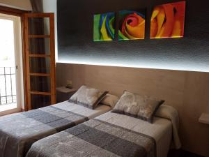 two beds in a room with paintings on the wall at Hostal Rural Rambla in Alcalá del Júcar