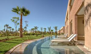una piscina del resort con sedie a sdraio e palme di Be Live Collection Marrakech Adults Only All inclusive a Marrakech