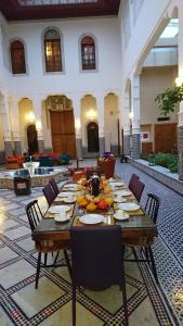 een lange houten tafel in een grote kamer met stoelen bij Riad jasmins & Spa in Fès