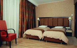 a bedroom with two beds and a red chair at Hotel Makedonia in Veria