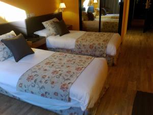 Habitación de hotel con 2 camas y espejo en Aeropuerto Madrid Torre Hogar Premium, en Torrejón de Ardoz