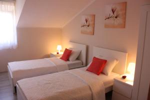 two beds with red pillows in a room at Apartments Tanja & Josipa in Pag