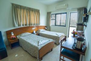 a hotel room with two beds and a window at YMCA International House in Mumbai