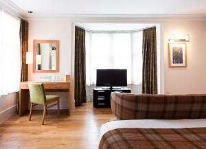 a hotel room with a bed and a desk and a television at ABode Canterbury in Canterbury