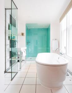 a white bathroom with a tub and a glass shower at ABode Canterbury in Canterbury