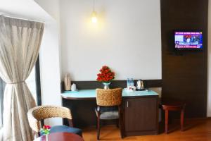 a room with a table and chairs and a tv at Ashraya International Hotel in Bangalore