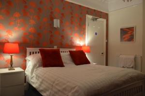 a bedroom with a bed with orange floral wallpaper at Audley Guest House in Llandudno