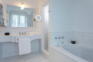 a white bathroom with a tub and a sink at Anna Belle Elegant AgriResort in Sorrento
