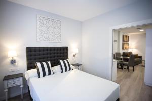 グラナダにあるLa Casa de la Trinidad Suitesのベッドルーム(大きな白いベッド1台付)、リビングルームが備わります。