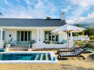 a house with a pool and two chairs and an umbrella at La Cotte Orchard Cottages in Franschhoek
