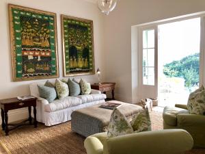 ein Wohnzimmer mit einem Sofa, Stühlen und einem Fenster in der Unterkunft La Cotte Orchard Cottages in Franschhoek