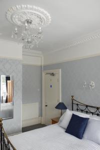 1 dormitorio con cama y lámpara de araña en Audley Guest House en Llandudno