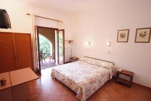 カポリーヴェリにあるHotel Voce del Mareのベッドルーム1室(ベッド1台付)、パティオへのドアが備わります。