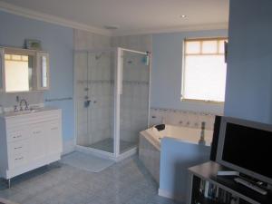 a bathroom with a shower and a tub and a television at Ocean View Retreat in Jurien Bay