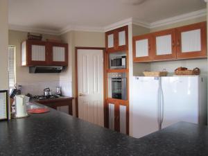 a kitchen with a white refrigerator and wooden cabinets at Ocean View Retreat in Jurien Bay
