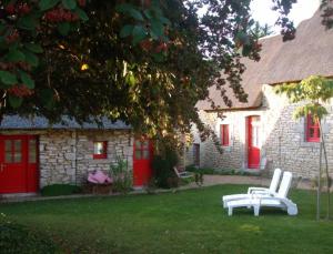 une maison aux portes rouges et un banc blanc dans la cour dans l'établissement La Sirène Endormie, à Penmarcʼh