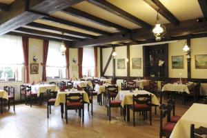 Hotel zur Post في Deudesfeld: غرفة طعام مع طاولات وكراسي وطاولات بيضاء وكرسي