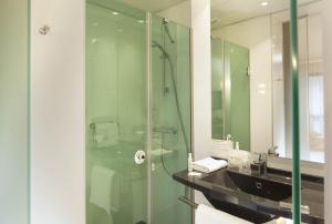 a bathroom with a shower, sink, and mirror at Escale Oceania Nantes in Bouguenais