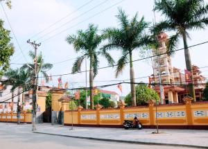 a motorcycle parked next to a yellow fence with palm trees at Sunflower Hotel in Ninh Binh
