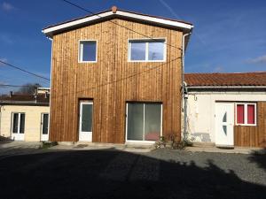 un bâtiment en bois avec deux fenêtres et un garage dans l'établissement Etablissements Coulon - Talence (Chemin d'Ars), à Talence