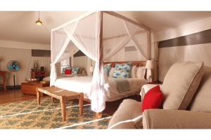 a bedroom with a canopy bed and a couch at Vertigo Lodge de Estaurio in Inhambane