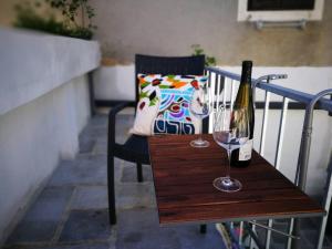 a wooden table with a bottle and a wine glass at cres art studio lime apartment in Cres