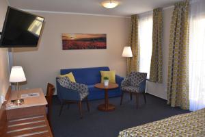 プラハにあるアパートホテル オーストリア スイーツの青いソファ、テーブルと椅子が備わるホテルルームです。